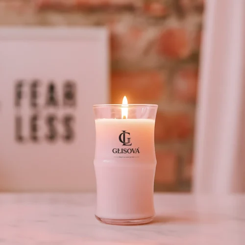 Luxury scented candle 'Offshore' lit on a marble surface with a 'Fear Less' sign
